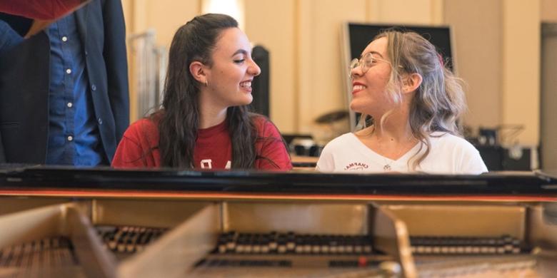 Two 澳门威尼斯人app下载大学 students playing piano